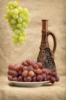Still life grapes and wine in bottle on sacking background