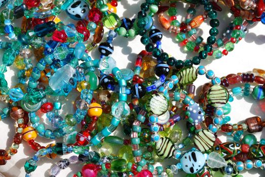 Coroful necklaces and bracelets with sunlight over white background.