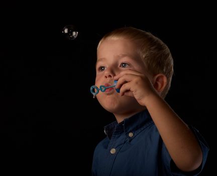 Little boy having fun blowing soap bubbles