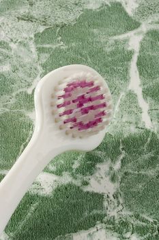 White tongue brush on the green countertop.