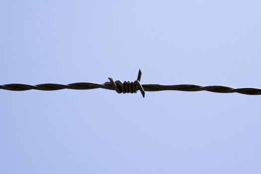 close up of barb wire fence on a blue sky background