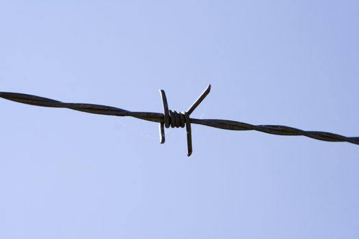 close up of barb wire fence on a blue sky background