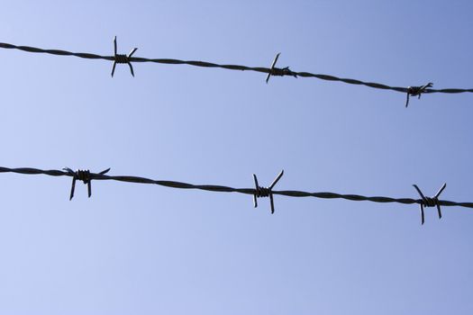 close up of barb wire fence on a blue sky background