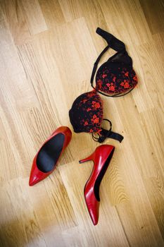 fashionable female shoes and bra on wooden floor