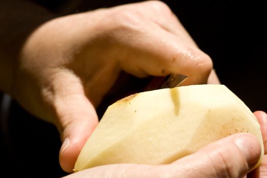 a women peeling a potato close up of the womens hands