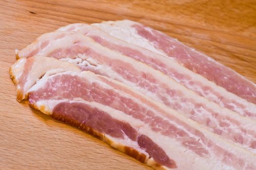 sliced raw bacon on a wood cutting board