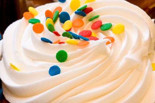 freshly baked cupcakes close up with colored candies on the frosting