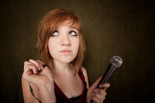 Pretty young girl with red hair on a green background with microphone