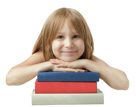 Young girl leaned over pile of books, isolated on white. Six years old, blonde, caucasian, smiling.