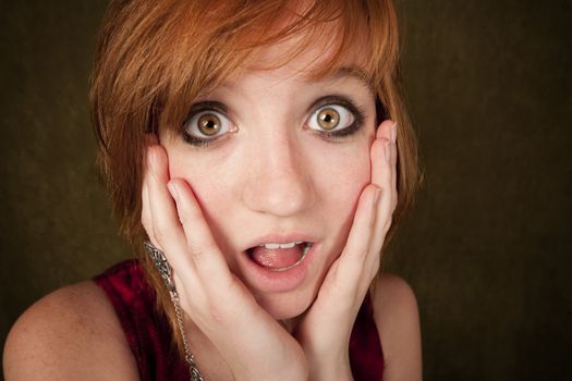Shocked pretty young girl with red hair on a green background