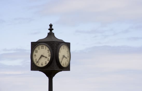 old clock on a blue sky two faces shot at a 45 degree angle