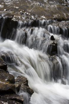 small stream water cascading over a rocky riverbed slow shutter speed nice silky smooth falls