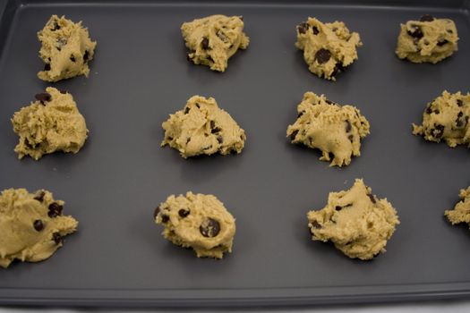 A cookie sheet of chocolate chip cookies ready for the over.