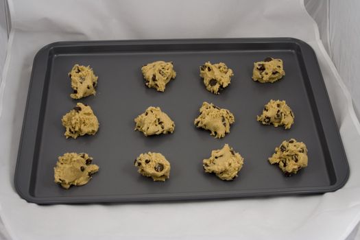 A cookie sheet of chocolate chip cookies ready for the over.