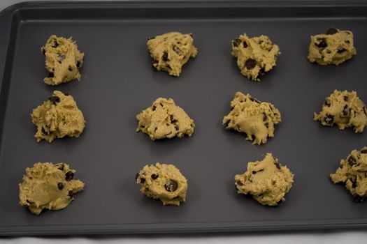 A cookie sheet of chocolate chip cookies ready for the over.