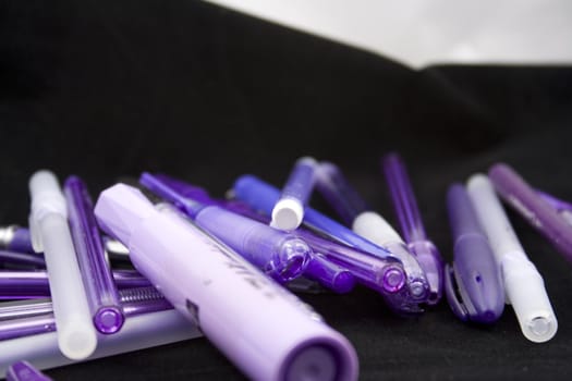 Pile of purple pens just waiting for someone to pick one up and start writing