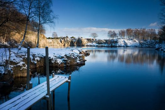 Wooden deck on the shore of a small lake in winter (Sweden).