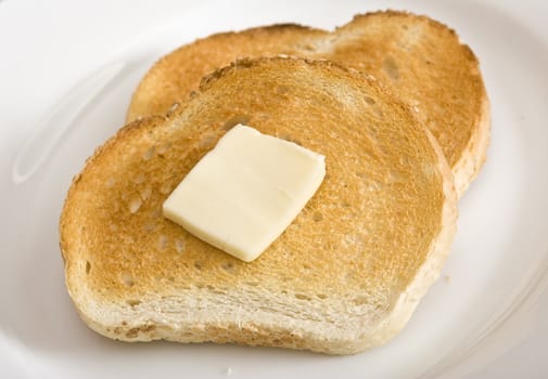 Two sllices of toast and a slice of butter on a white plate