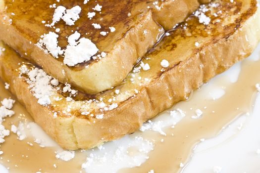 french toast on a white plate with powdered sugar and maple syrup 
