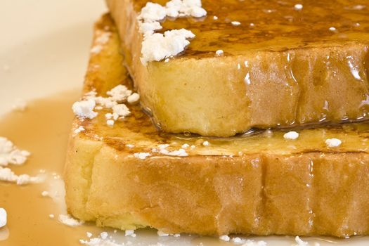 french toast on a white plate with powdered sugar and maple syrup 