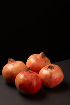 Several bright red ripe pomegranates on black background