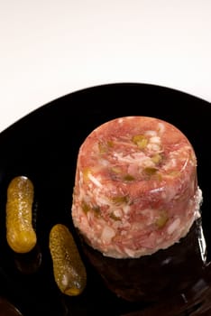 Pickled jellied meat served with some fresh gherkins.