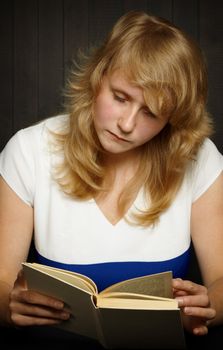 Young girl reading a book on a dark background