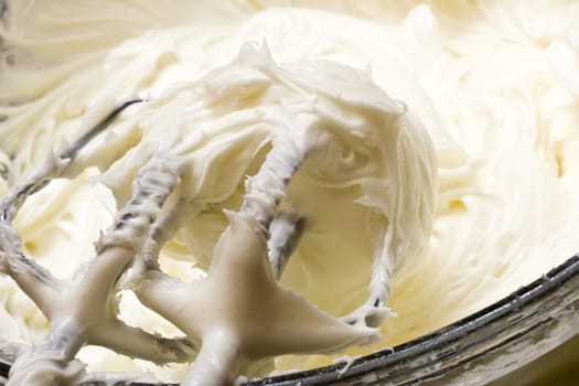 close up of cream cheese frosting mixed up in a glass bowl