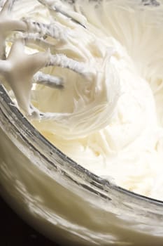 close up of cream cheese frosting mixed up in a glass bowl