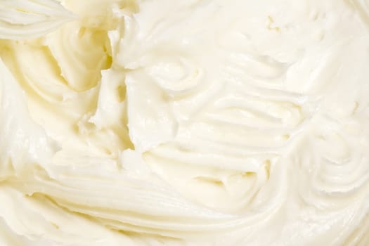 close up of cream cheese frosting mixed up in a glass bowl