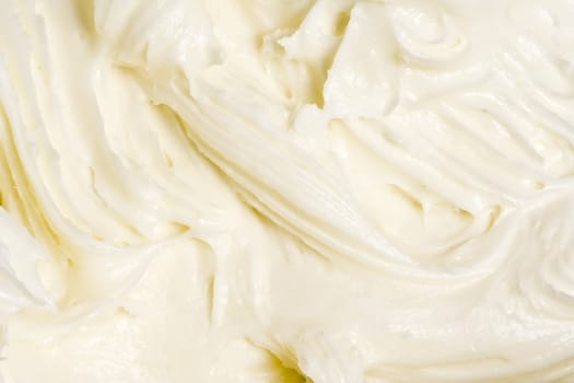 close up of cream cheese frosting mixed up in a glass bowl
