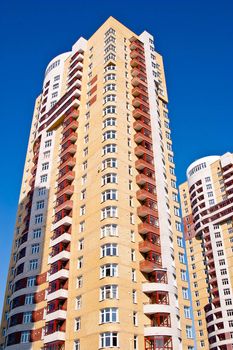 Modern tall residential building on a background of blue sky.