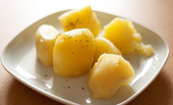 Boiled potatoes and greens on a plate. The back light.