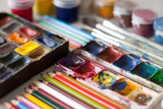Items for drawing and art: watercolor paint, brushes, colored pencils.