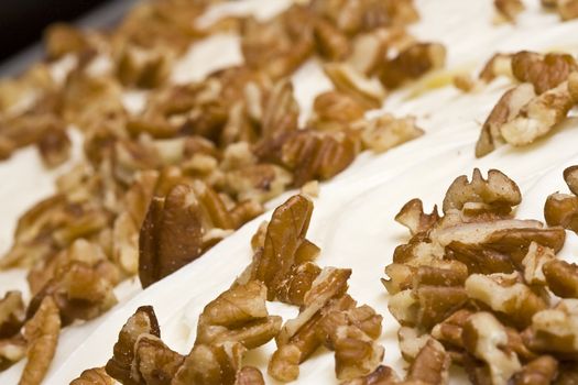 detail of the nuts on top of a slice of pumpkin cake with cream cheese frosting