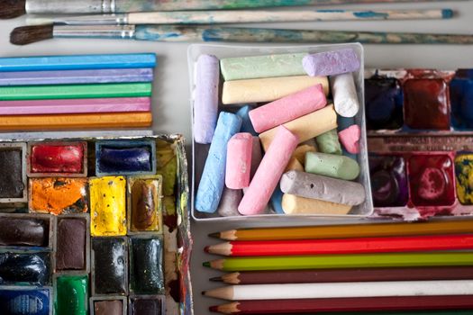 Items for drawing and art: crayons, watercolor paints, brushes, colored pencils.