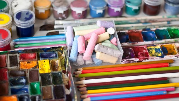 Items for drawing and art: crayons, watercolor paints, brushes, colored pencils.