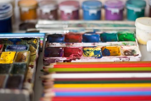 Items for drawing and art: watercolor paint, brushes, colored pencils.