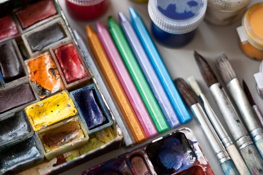 Items for drawing and art: watercolor paint, brushes, colored pencils.