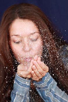 young brunette woman blowing metallic confetti