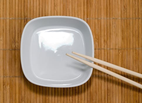 Plate and chopsticks against bamboo mat
