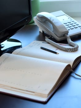 Personal workplace: table, monitor, business is a diary and telephone. Conception of office work.