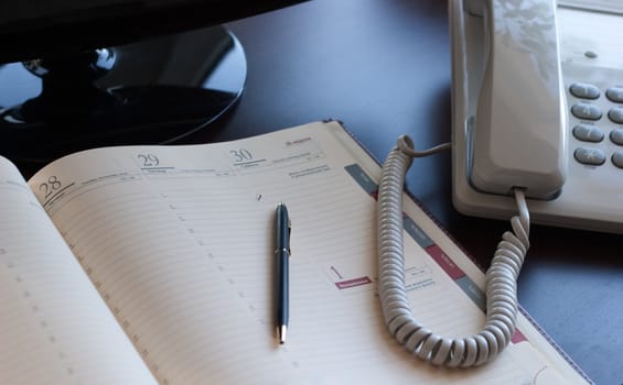 Personal workplace: table, monitor, business is a diary and telephone. Conception of office work.