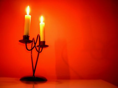 two burning candles on candlestick over orange
