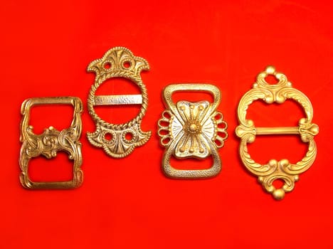 four silver buckles over red background       
