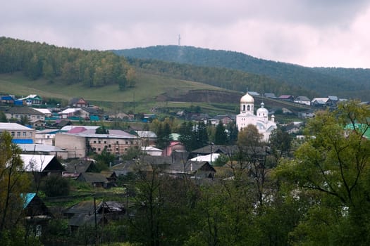 Russian small town: the hills, houses and a church. Gloomy weather