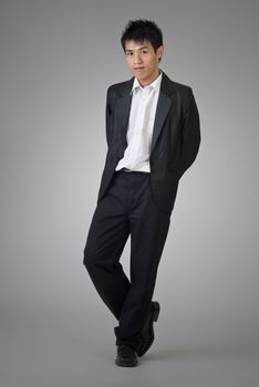 Attractive Asian business man posing on studio gray background.