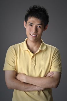 Handsome Asian guy, closeup portrait with smiling expression over studio gray background.