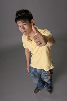 Asian young guy give you excellent sin over studio gray background.