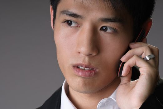 Handsome young business man using cellphone, closeup portrait over studio gray background.